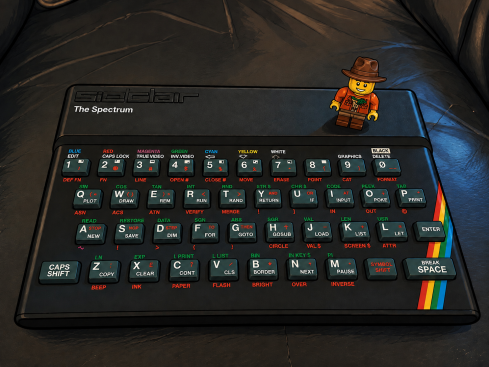A vintage Sinclair ZX Spectrum computer keyboard with a small LEGO explorer figure standing on it.